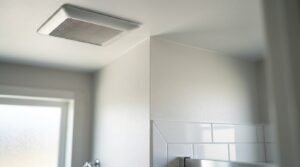 Ceiling-mounted white bathroom exhaust fan installed near tiled walls to control indoor humidity and prevent mold growth after water damage.